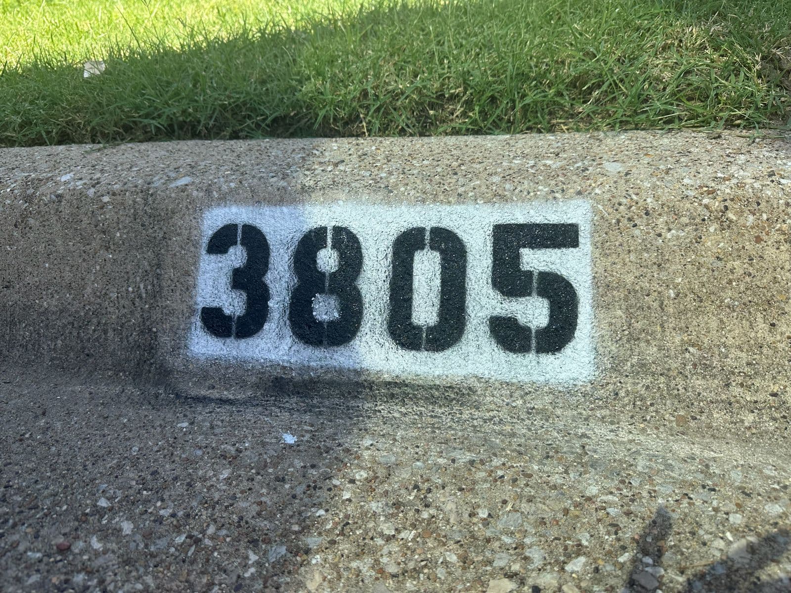 Close-up of curb number 3805 in bold black stencil numerals on a bright white background
