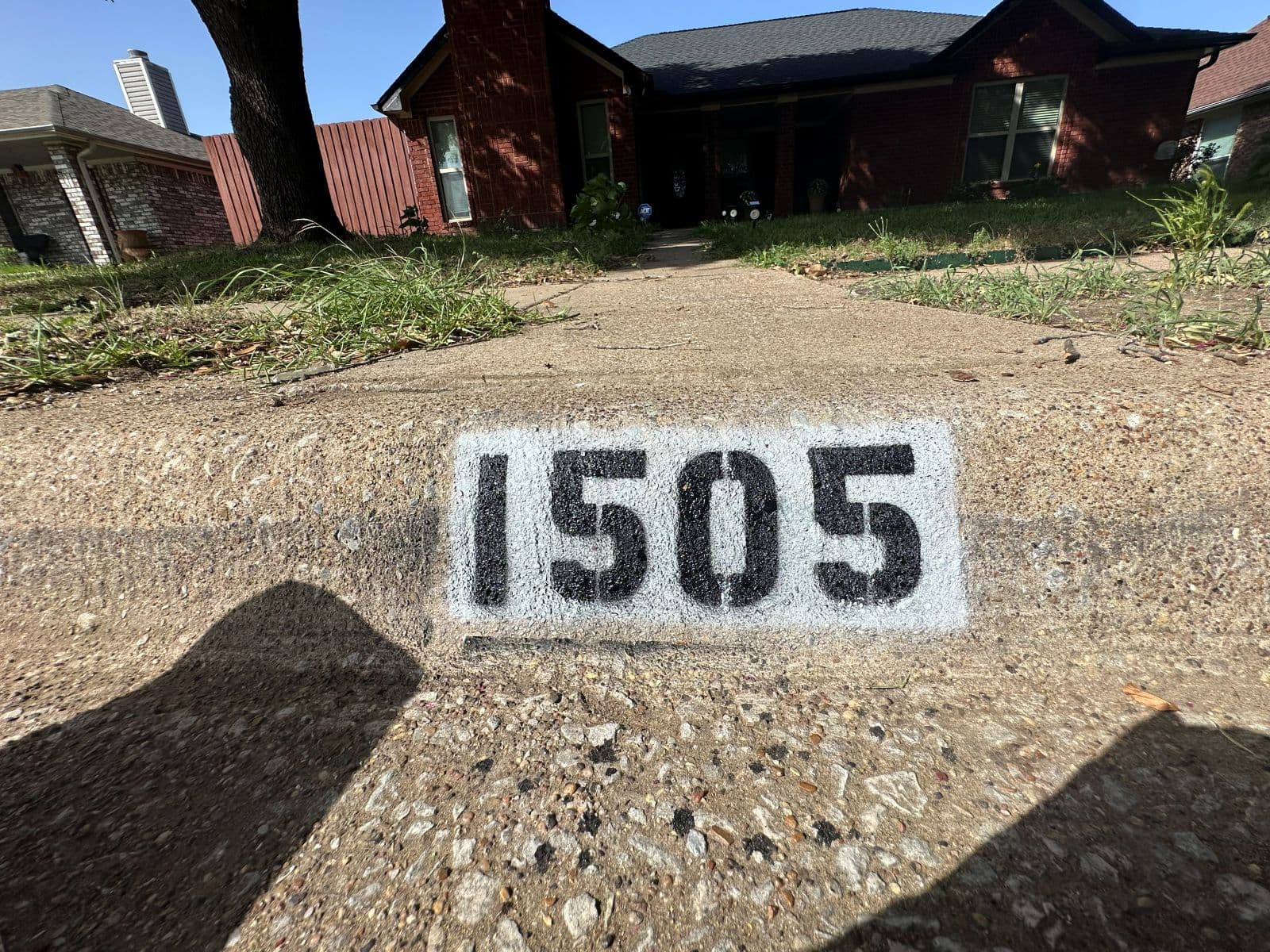 Curb address 1505 painted in crisp black numbers on white outside a red-brick home