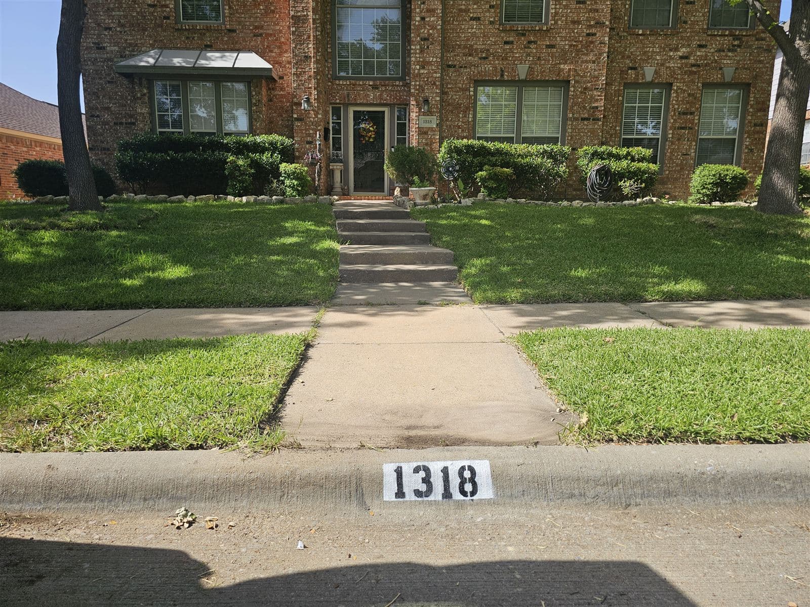 House number 1318 painted on the curb in bold black numerals on a clean white background